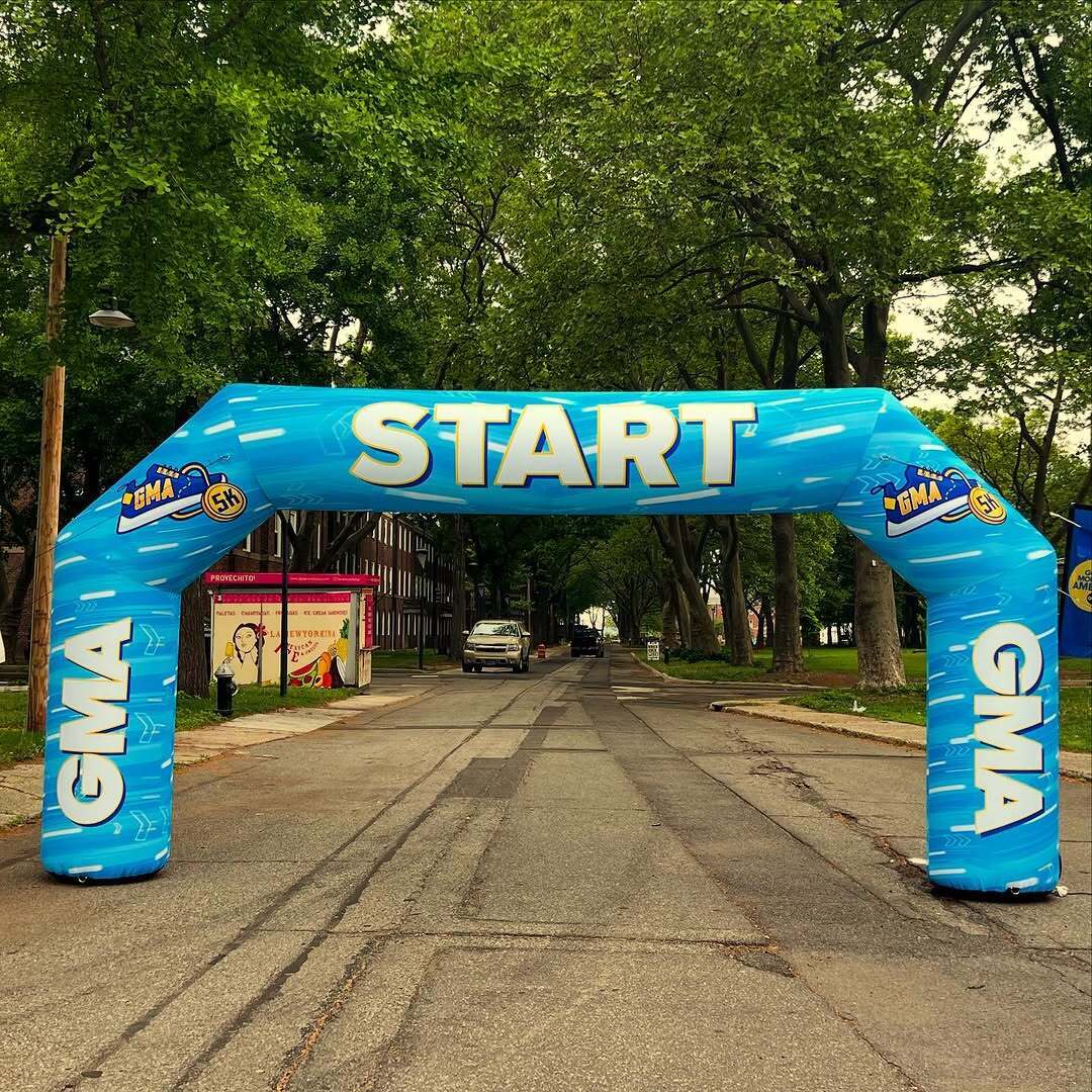 Inflatable blue GMA 5K start line arch set up on a city street lined with trees