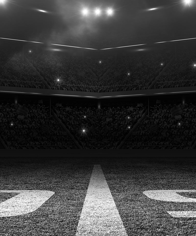 Monochrome image of a packed stadium with illuminated field lines for a sporting event.