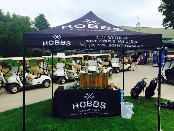Hobbs Tavern & Brewing tent with branding at an outdoor event with golf carts in the background.