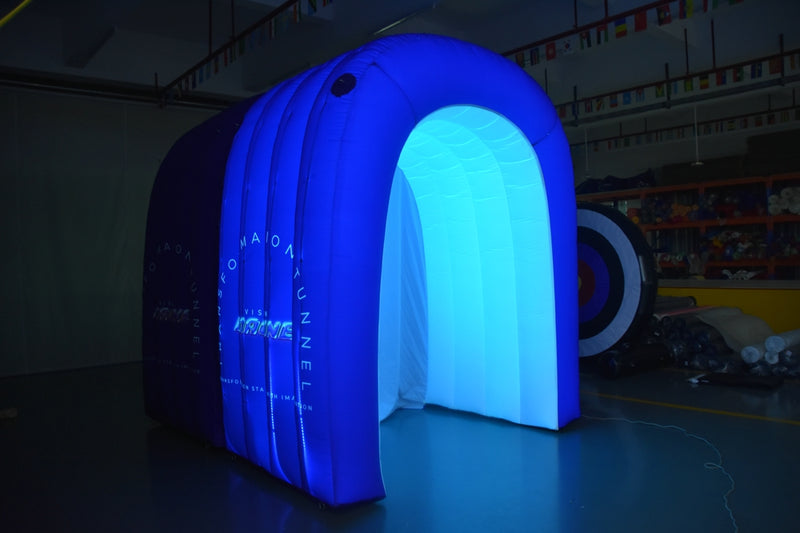 Blue inflatable tunnel with LED illumination glowing in a dimly lit indoor space, highlighting the dynamic lighting option.