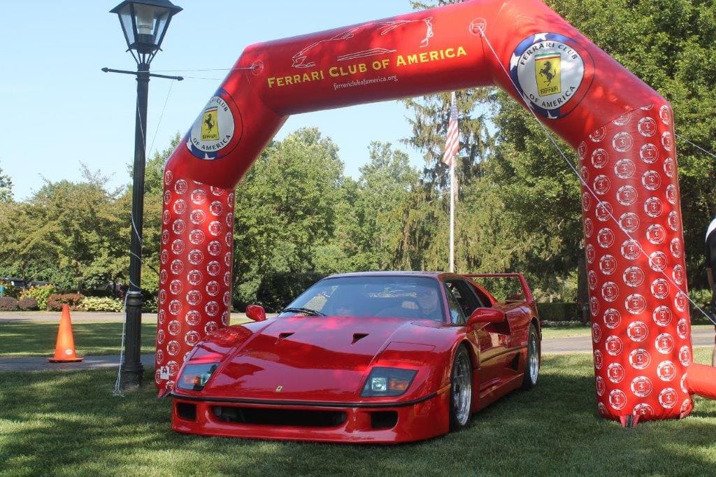 Red Ferrari sports car displayed under a custom inflatable arch branded for the Ferrari Club of America at an outdoor car show, created by MVP Visuals