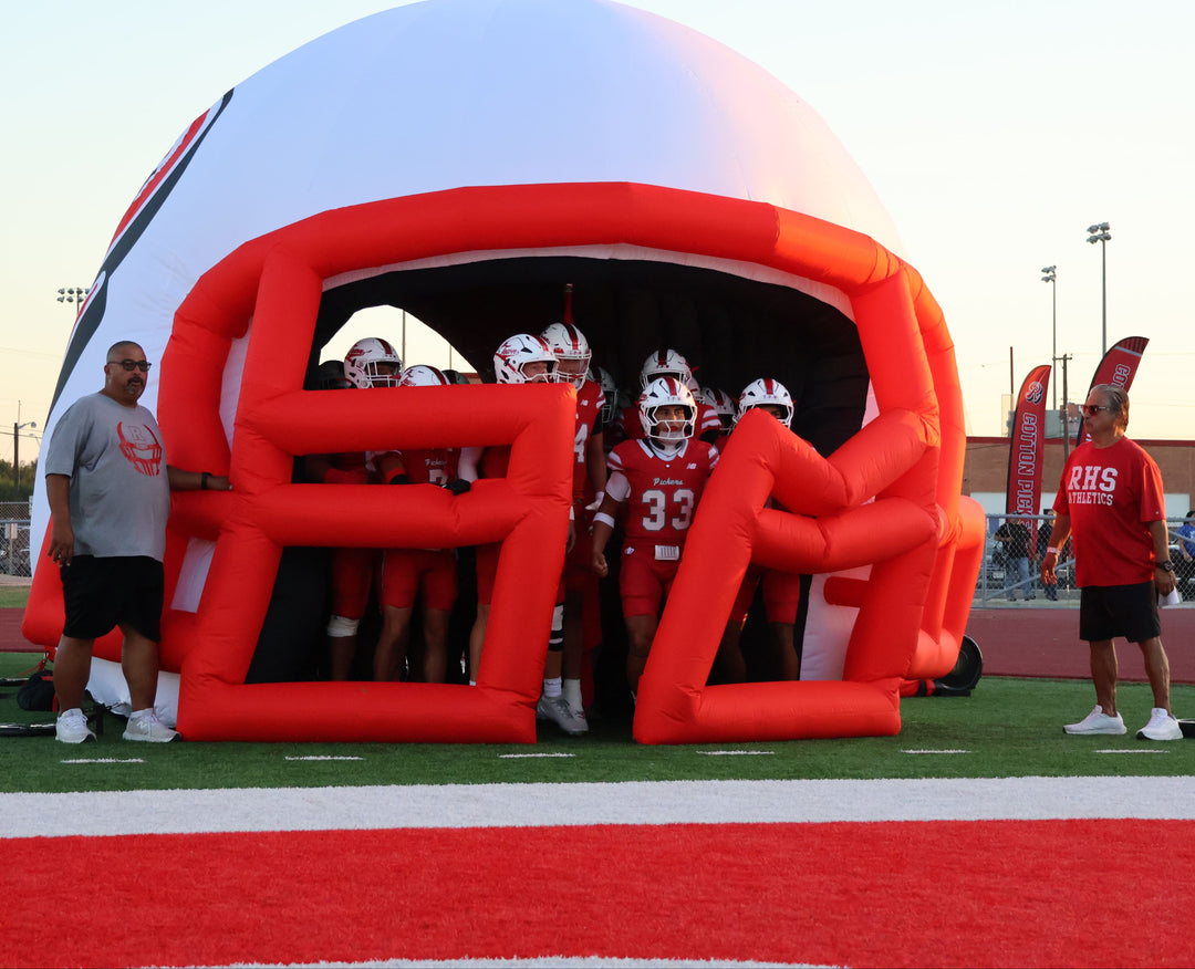 Inflatable football helmet tunnel with Cotton Pickers football players lined up inside ready to enter the field.