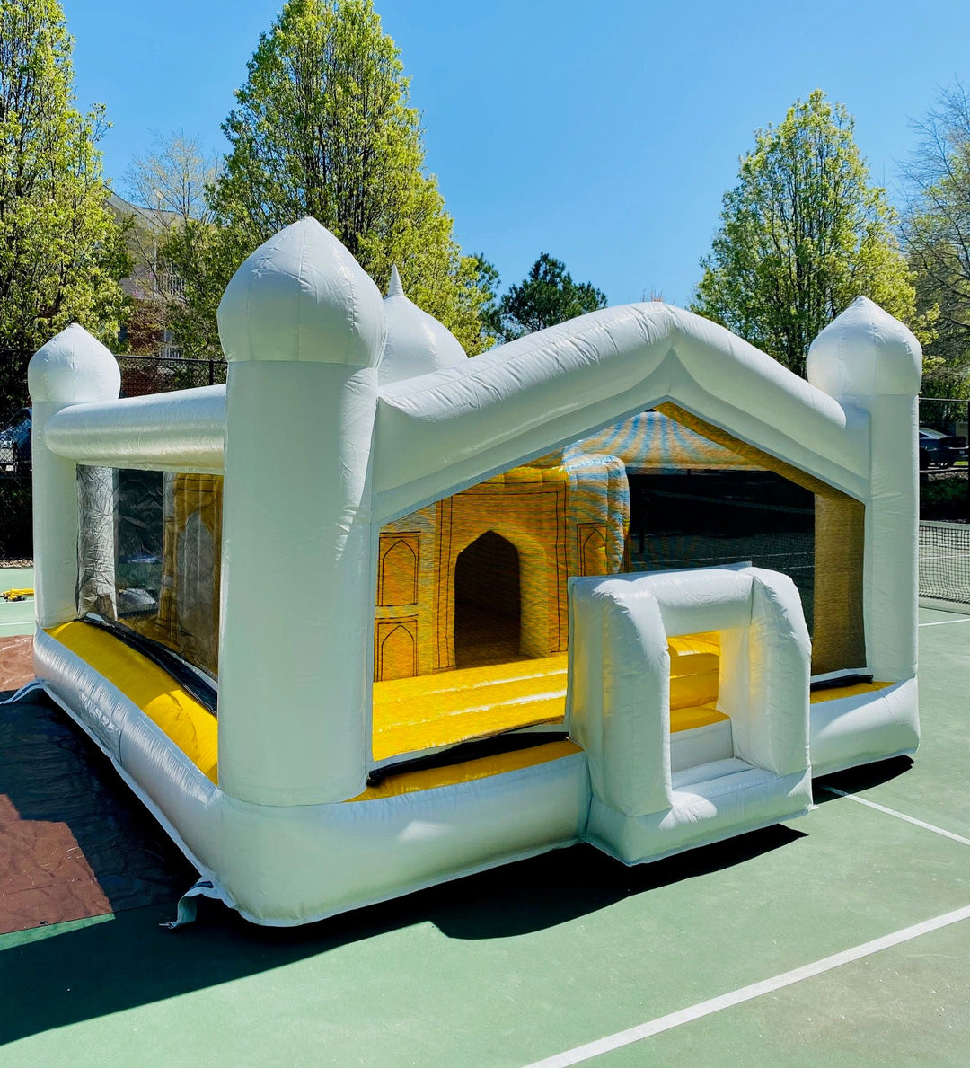White and yellow inflatable bounce house styled like the Taj Mahal on an outdoor tennis court
File name: inflatable-taj-mahal-bounce-house-court.jpg