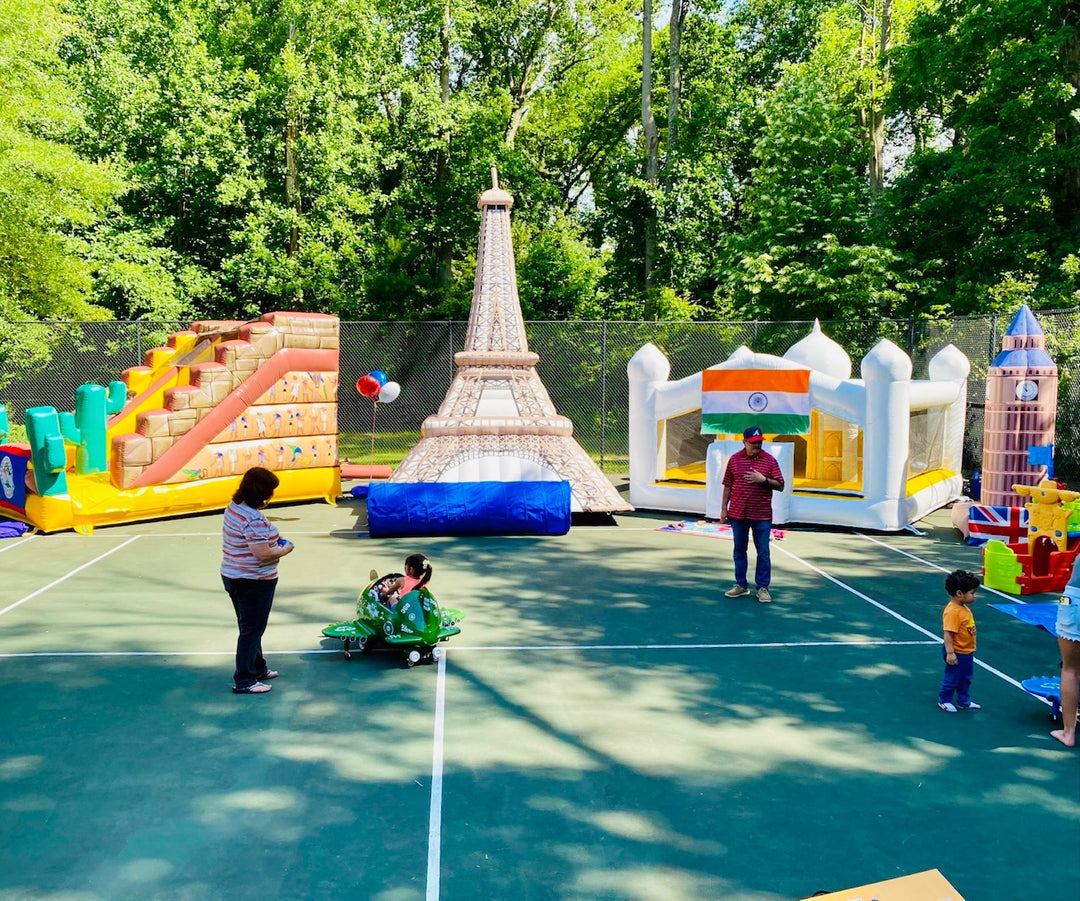 International-themed inflatable playground setup with Eiffel Tower, Taj Mahal, and Big Ben on a tennis court