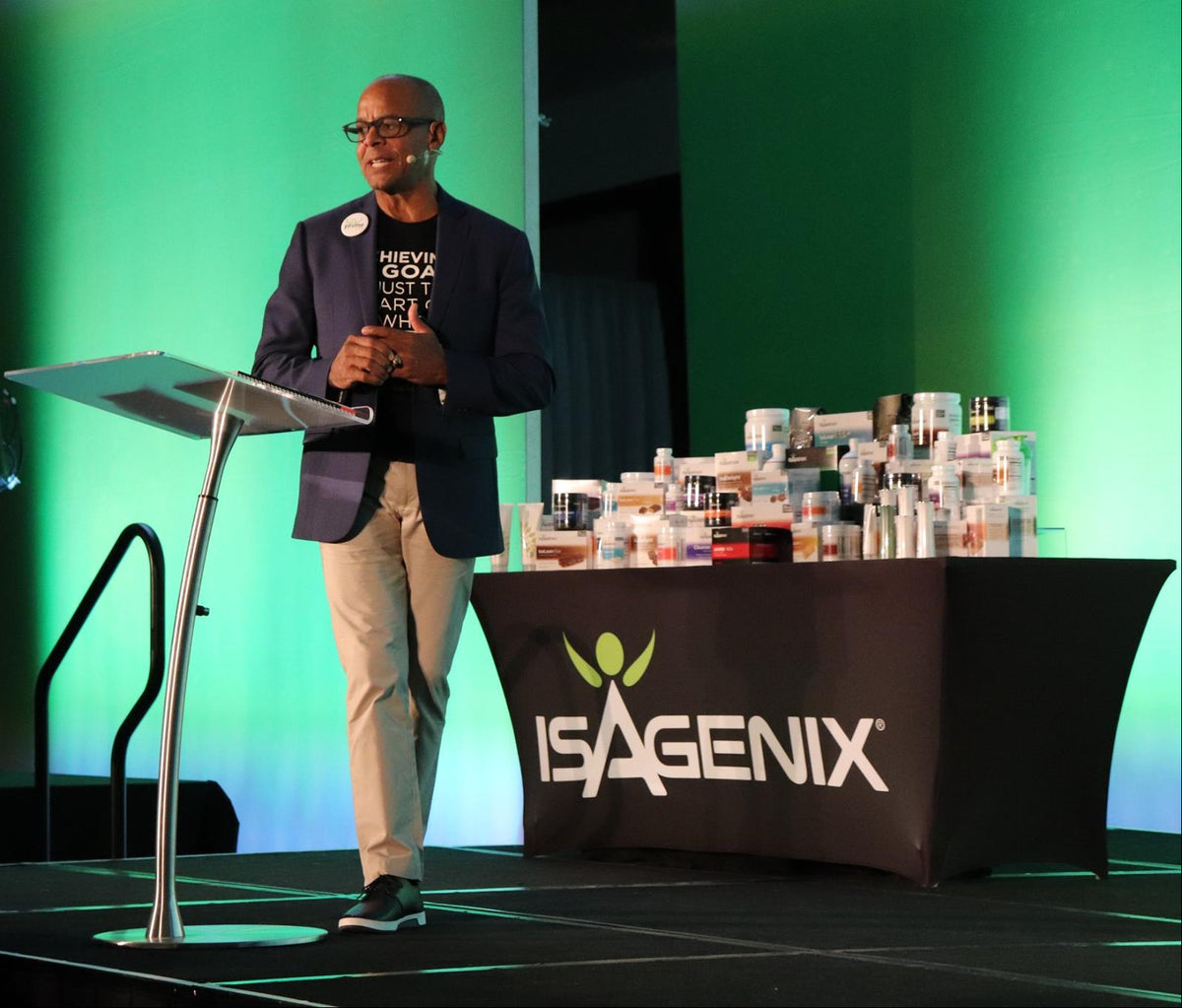 Man standing at a podium with Isagenix branding in the background