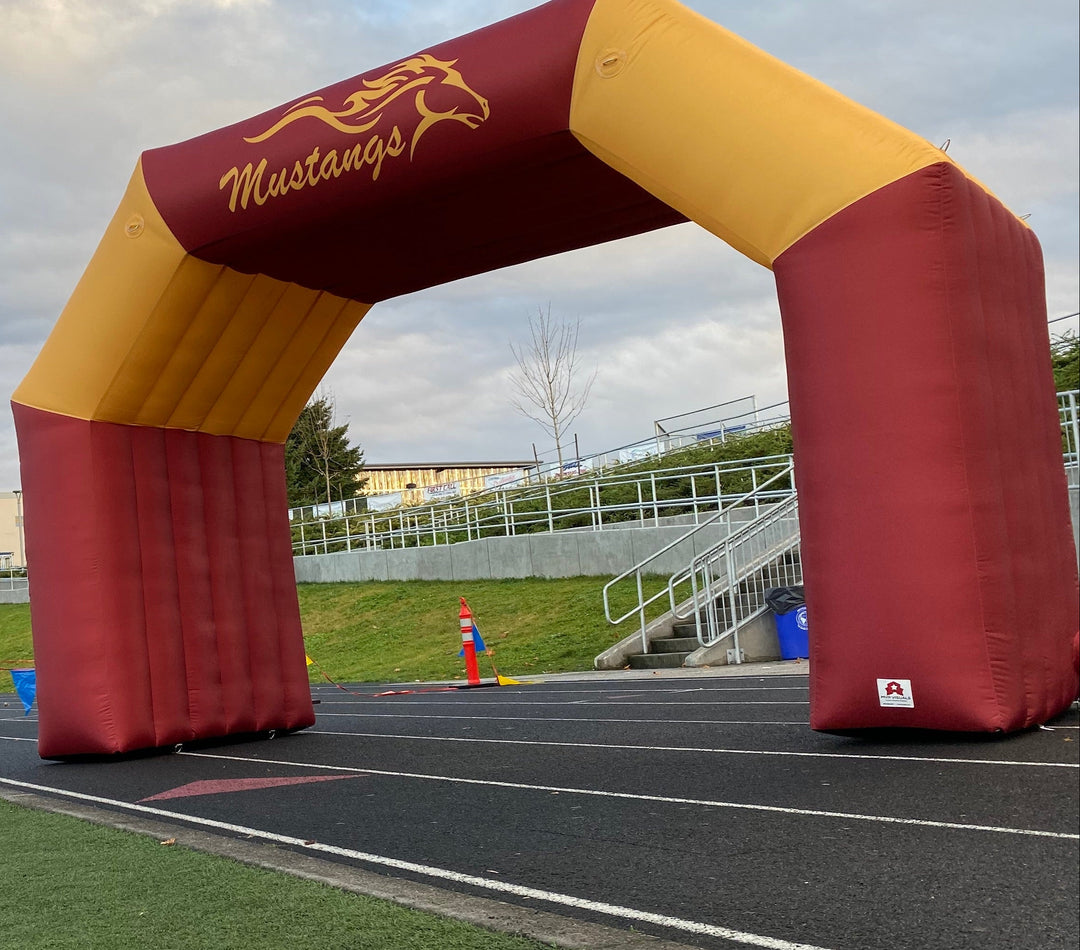 Custom inflatable archway in maroon and gold for Milwaukie High Mustangs on a school track