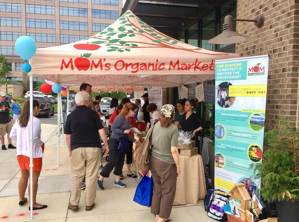 MOM’s Organic Market custom canopy tent at community outreach event with booth, signage, and customer engagement