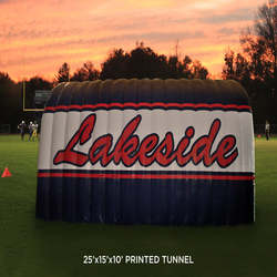 Large custom printed inflatable football tunnel with 'Lakeside' text at dusk on a high school football field