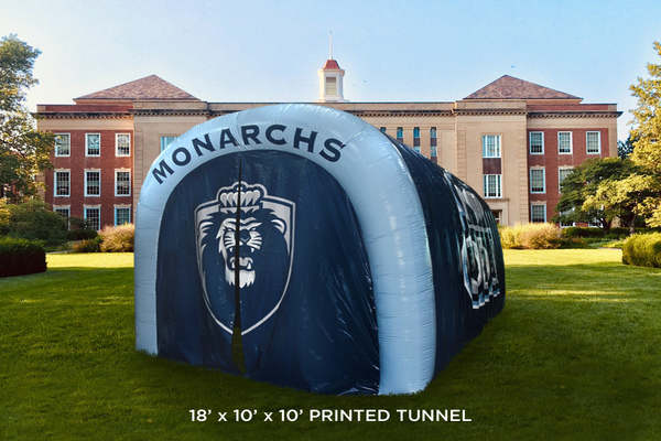 Custom 18' x 10' inflatable tunnel with 'MONARCHS' and a lion mascot logo displayed on the front, set on a school lawn with a building in the background
