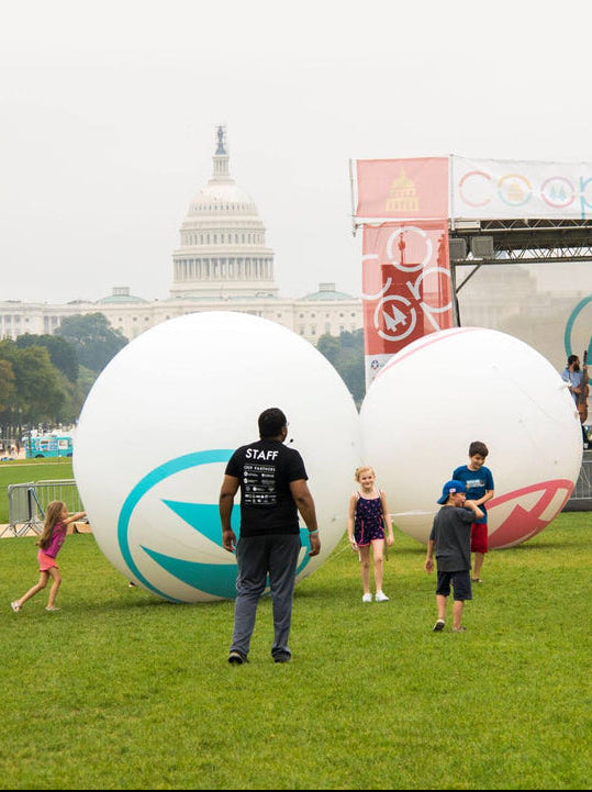 People interacting with large inflatable balls at a festival in front of a government building.