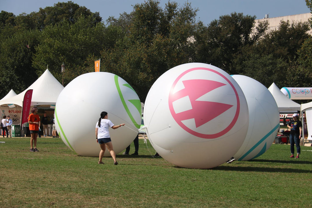 Volunteer guiding giant inflatable logo balls at NCBA event on the National Mall