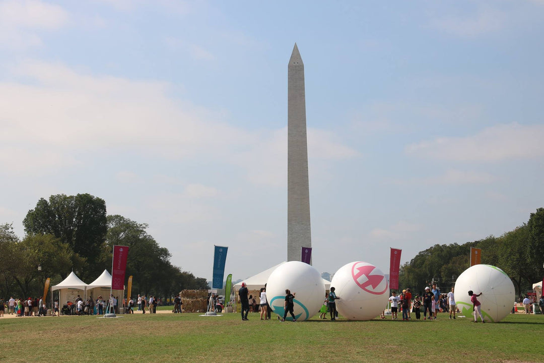 Children playing with large inflatable logo balls in front of the Washington Monument during NCBA event