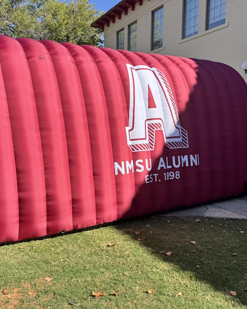 Red inflatable tunnel for NMSU Alumni event with large white "A" logo and "Est. 1898" text, custom branded for outdoor university use