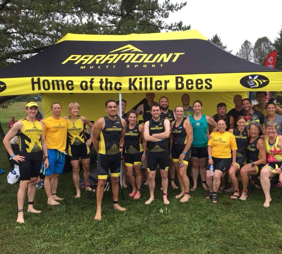 Paramount Multisport team posing under black and yellow tent