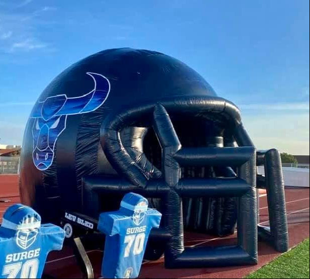 Inflatable football helmet tunnel with bull logo and tackling dummies at youth field