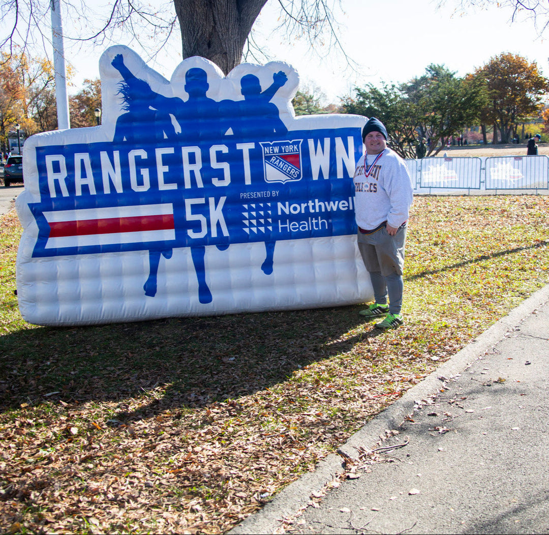 Participant poses with inflatable Rangerstown 5K sign at outdoor race event