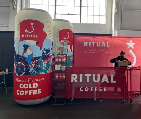 Ritual Coffee promotional setup with large inflatable coffee can models and branded backdrop.