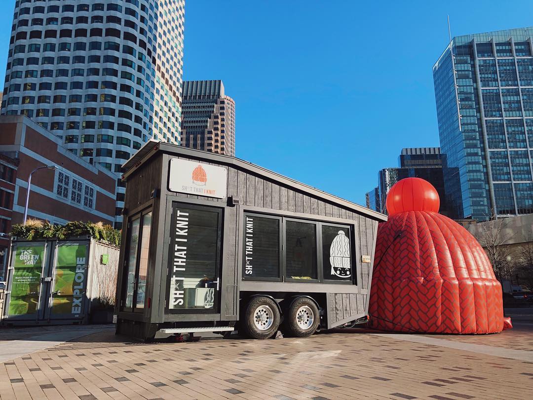 Sh*t That I Knit pop-up retail display with oversized knit hat installation in urban outdoor event space