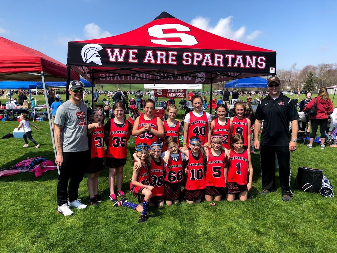 Somers Spartans custom canopy tent with youth girls lacrosse team posing at outdoor tournament