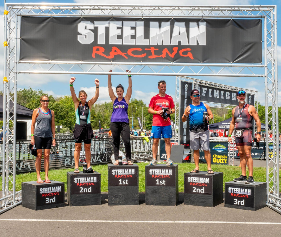 Steelman Racing event podium with male and female winners celebrating under custom event banner