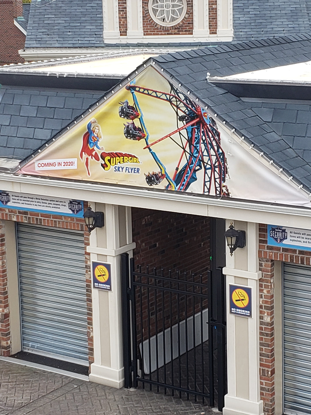 Vinyl gable banner featuring Supergirl and the Sky Flyer amusement ride, mounted on the triangular facade of a theme park building.