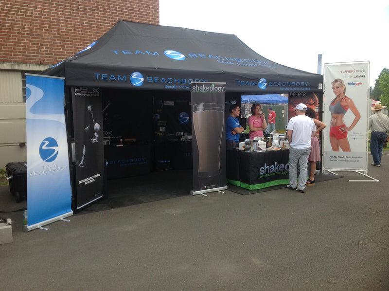 Team Beachbody 10x15 custom canopy tent with branded display, banners, and product sampling booth at outdoor fitness event