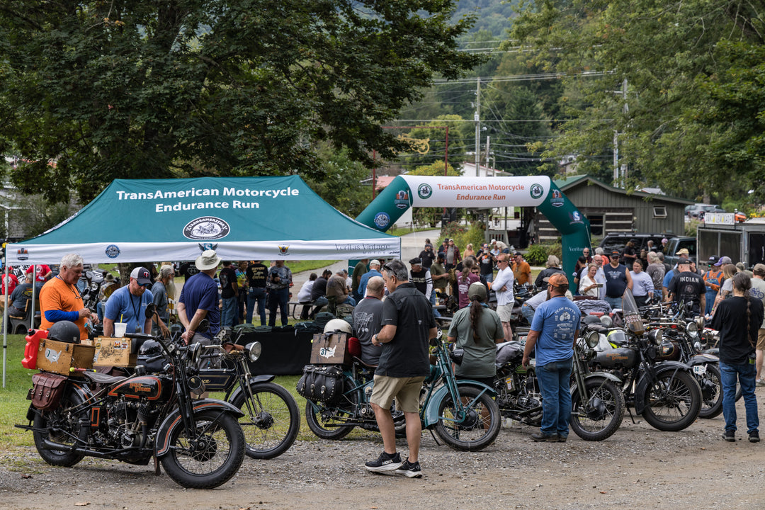 Inflatable arch and branded canopy at TransAmerican Motorcycle Endurance Run event with vintage motorcycles and a crowd of participants