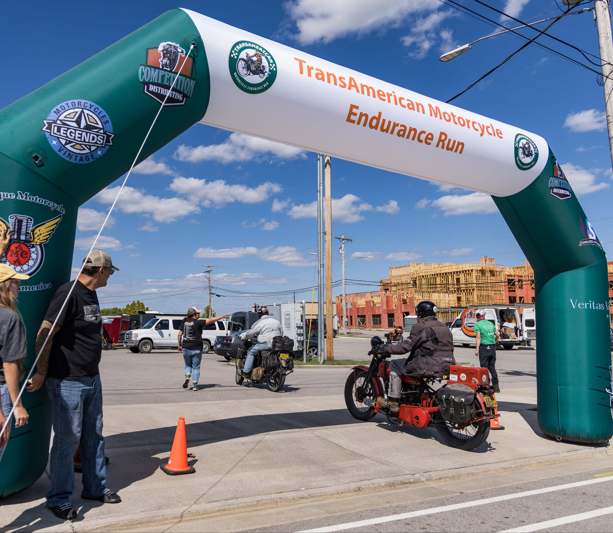 Riders passing through TransAmerican Motorcycle Endurance Run inflatable arch at event start