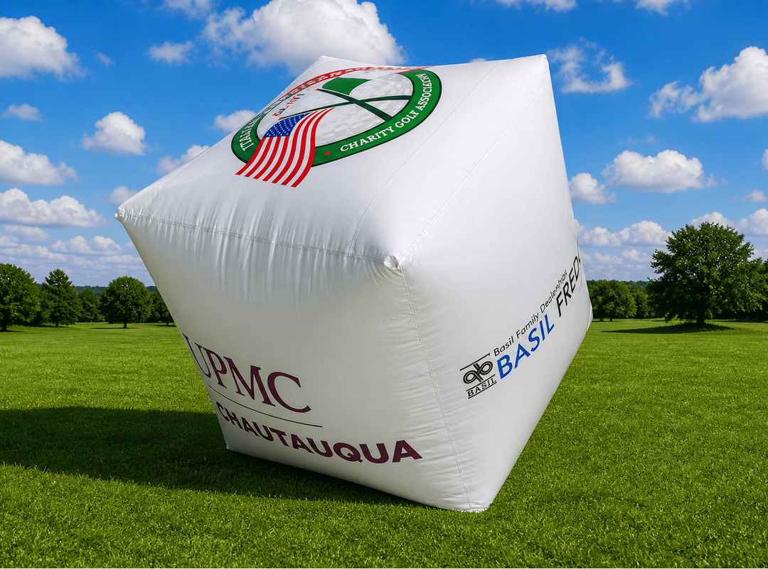 Inflatable cube with branding on a grassy field under a blue sky