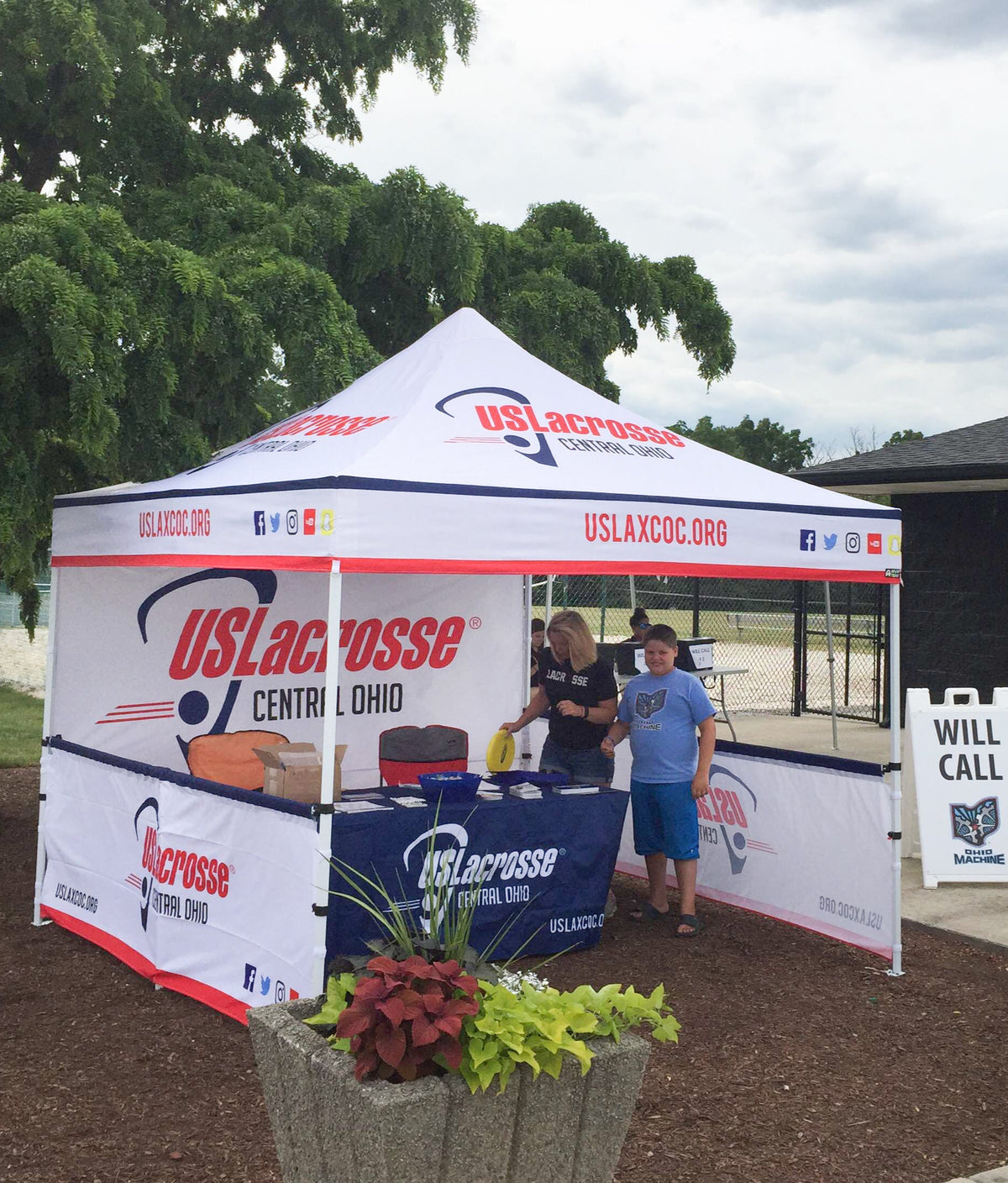 US Lacrosse tent with people around it outdoors