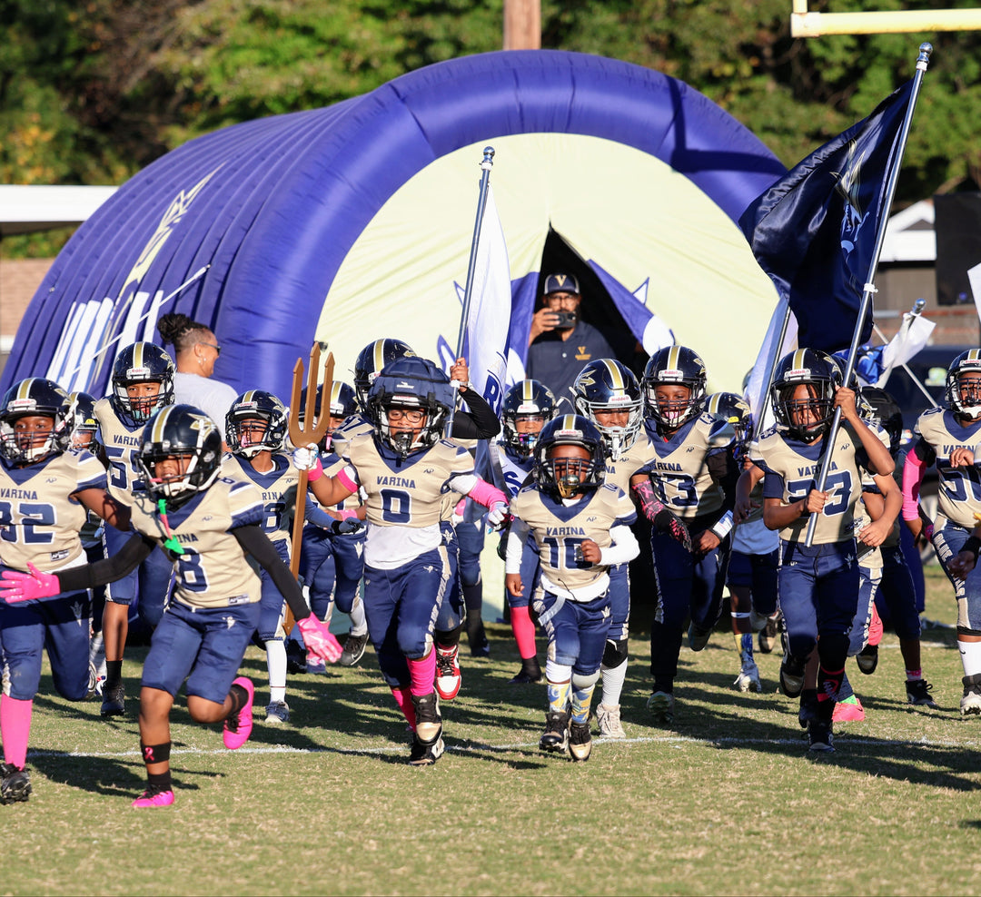 Varina Blue Devils youth football team running out of inflatable tunnel with flags and trident