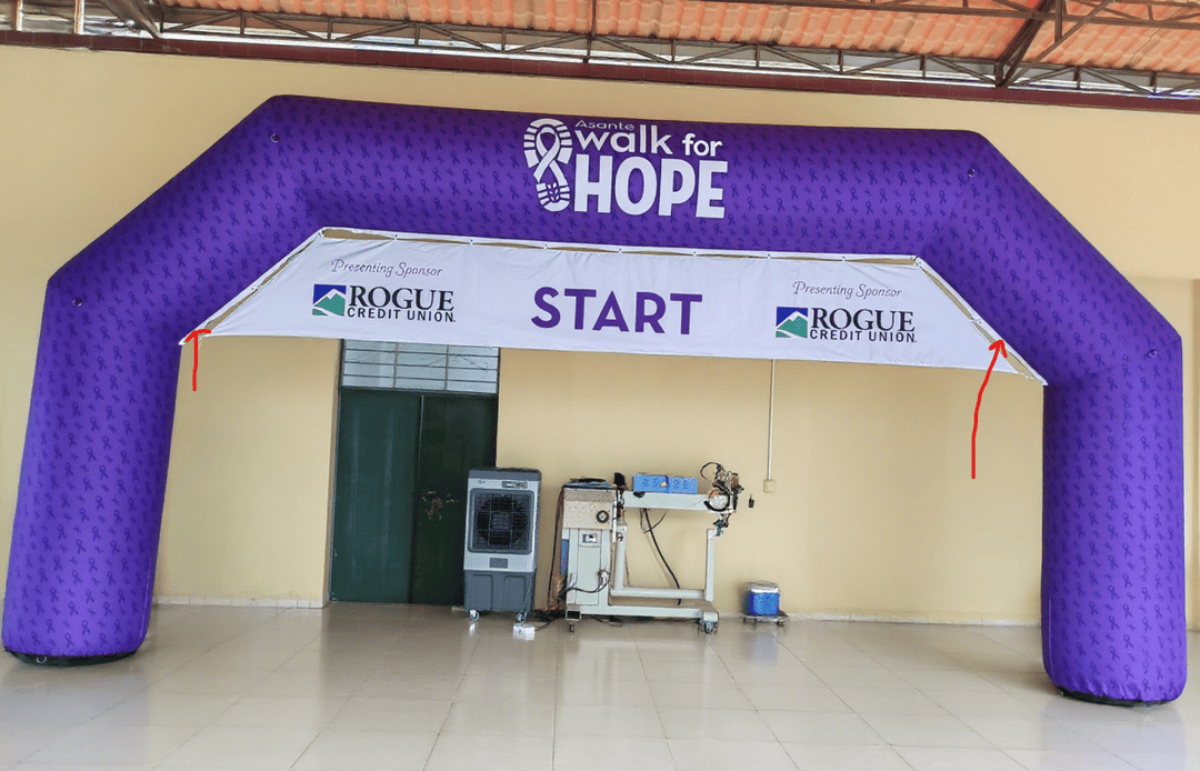 Purple inflatable arch for 'Walk for Hope' event with Rogue Credit Union sponsor logos and a START banner