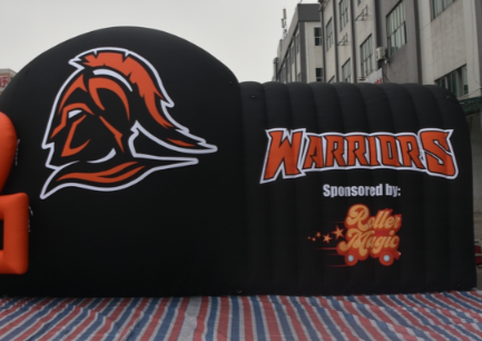 Side angle of Warriors inflatable football helmet tunnel with bold orange facemask