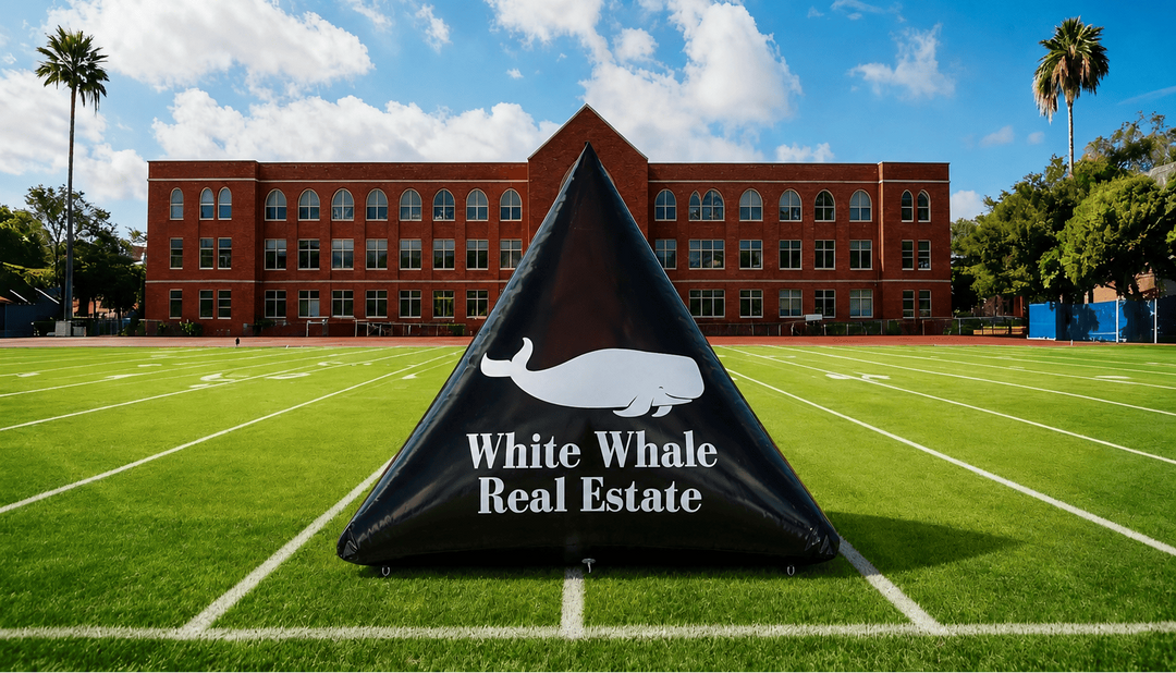 Black pyramid-shaped custom inflatable with 'White Whale Real Estate' logo on a grassy field with a building in the background.